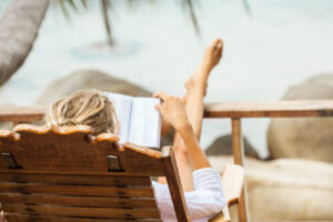 Cropped photo of woman reading a book at the beach.